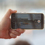 Ilustrasi seseorang merekam video secara diam-diam menggunakan smartphone dari belakang korban.